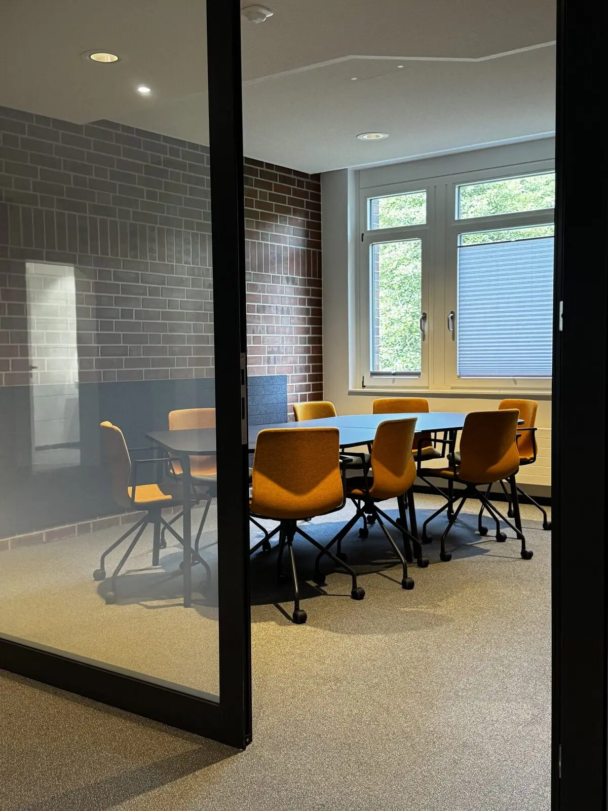 Verglaster Meetingraum mit Konferenztisch und akustisch gedämpften Wänden
